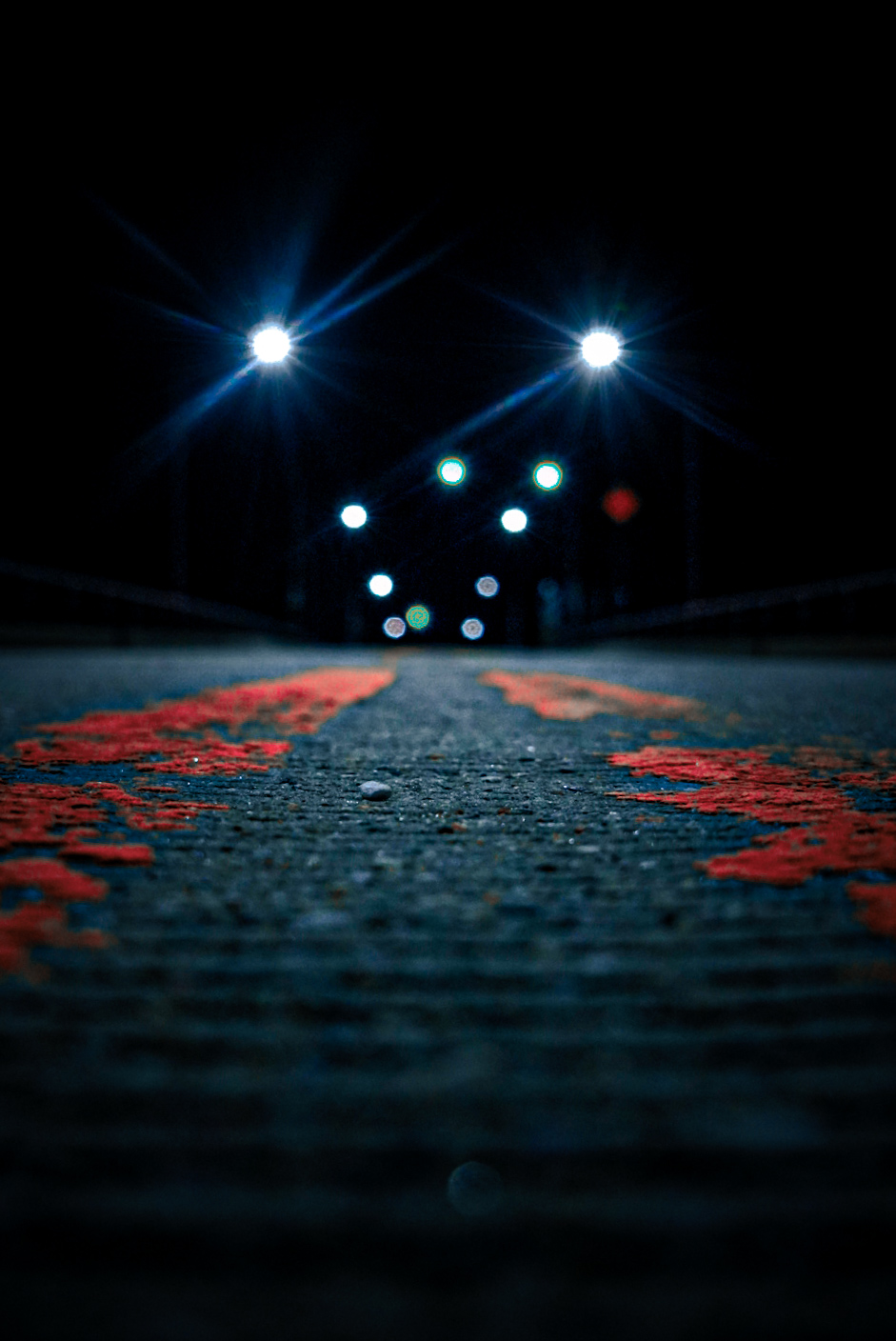 Low-angle night road with distant glowing lights