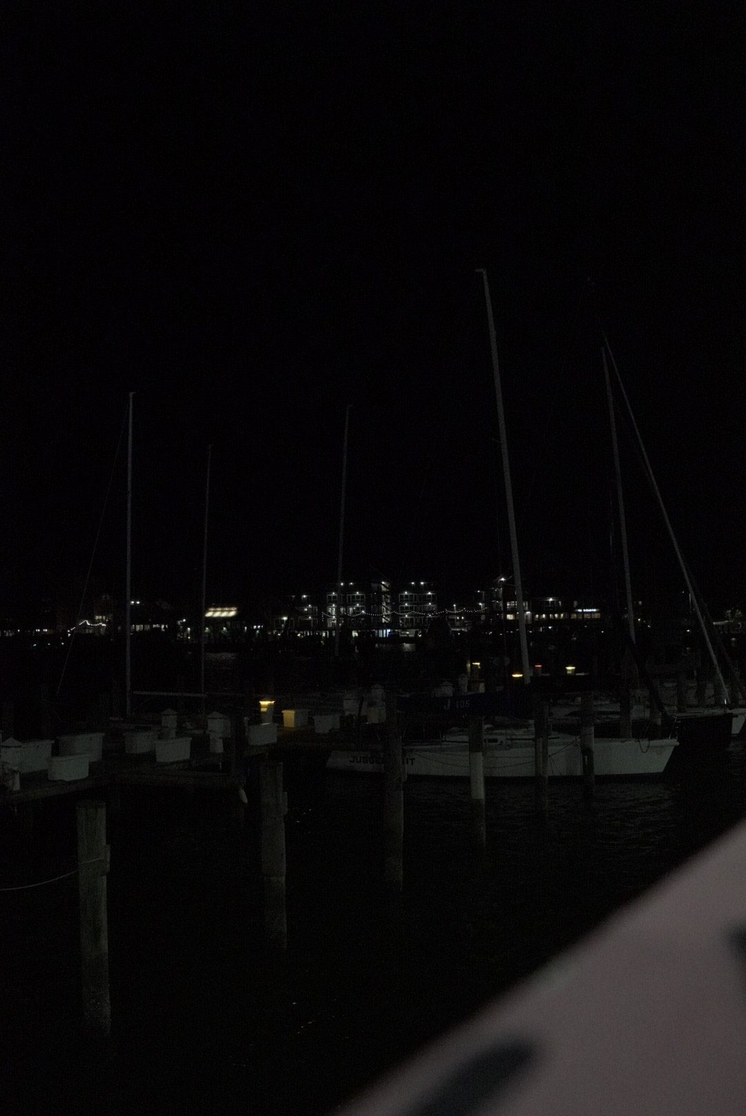 Sailboat masts against the harbor skyline at night